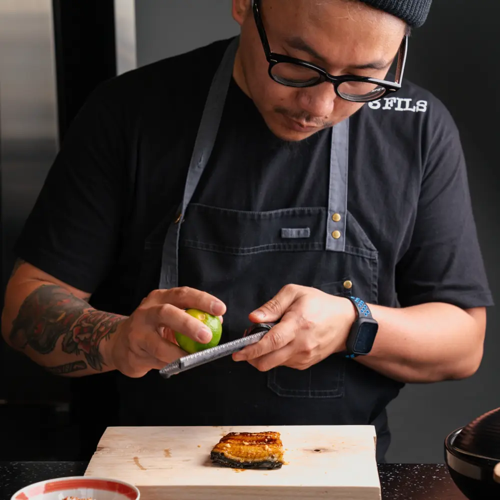 3Fils chef carefully zesting lime over grilled unagi